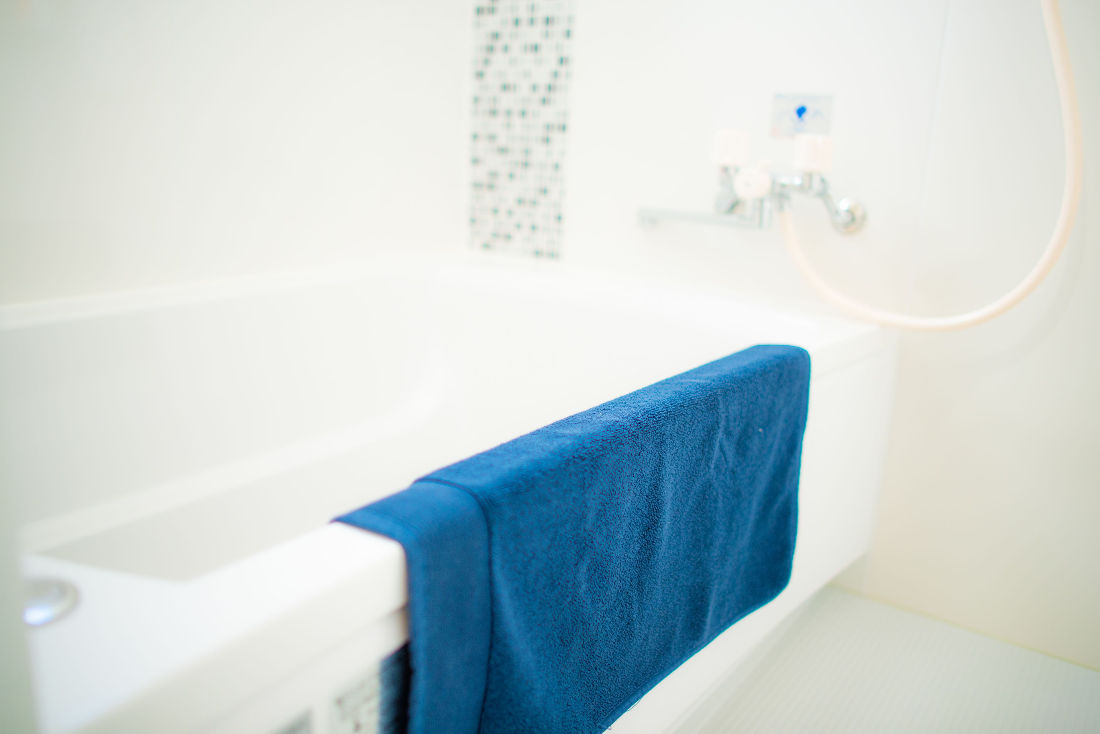 A bathroom with a white bathtub and a blue towel hanging on the side.