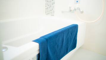 A bathroom with a white bathtub and a blue towel hanging on the side.
