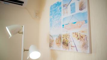 A wall with a beach-themed artwork and a white lamp.