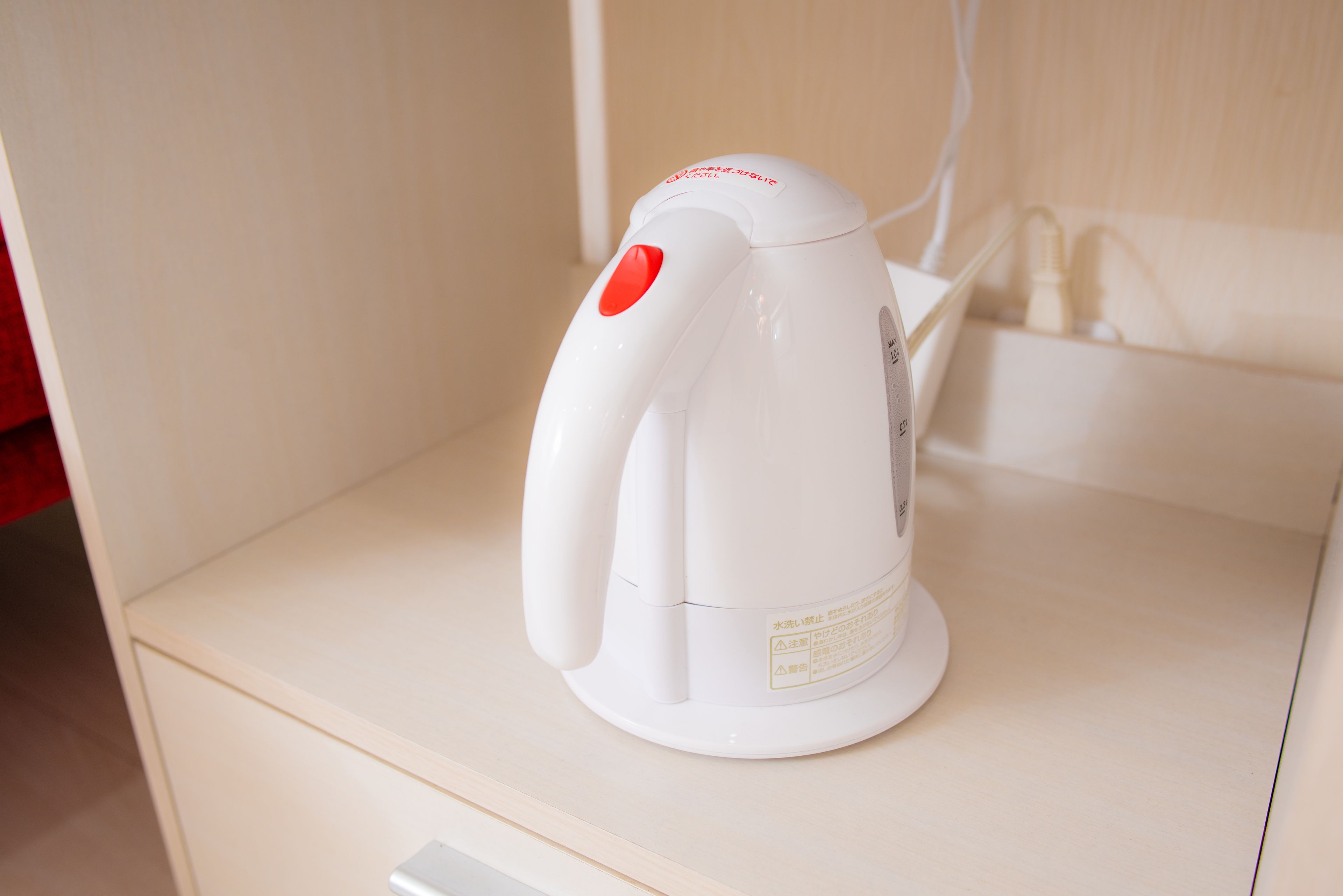 A white electric kettle on a wooden cabinet.