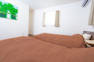Una habitación con una cama, una ventana con cortinas, un aire acondicionado instalado en la pared y un cuadro.