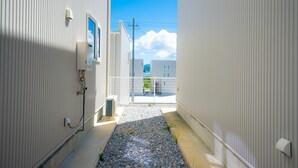 Een smalle steeg met een grindpad, witte gebouwen en een helderblauwe lucht.