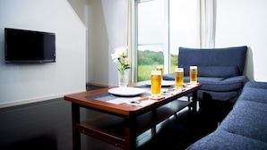 Een moderne woonkamer met een eettafel gedekt voor twee personen, een flatscreen-televisie aan de muur en een bank.