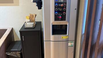 Uma geladeira compacta com visor digital, dispenser de água e uma pequena lixeira.
