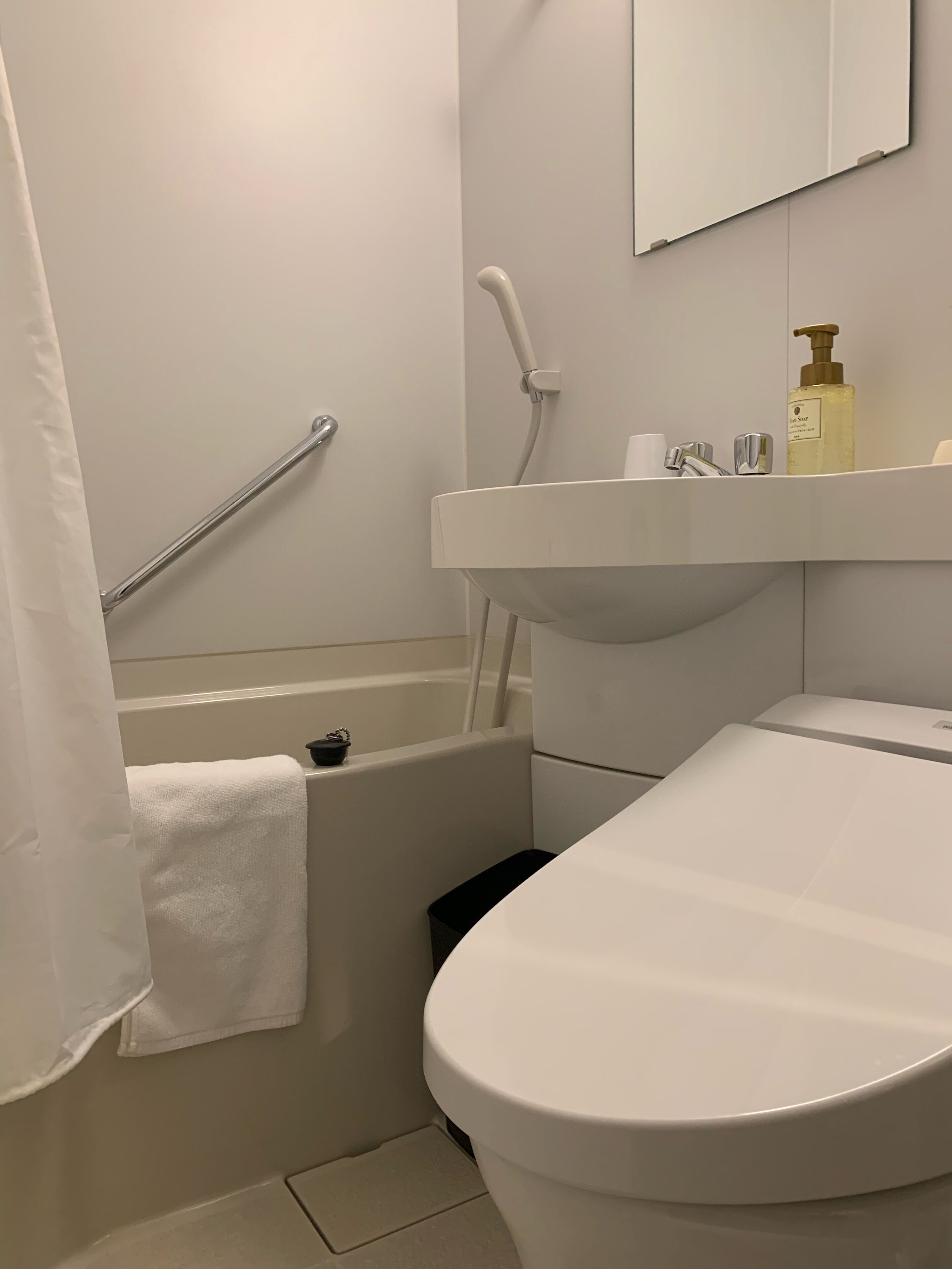 Une salle de bain avec une baignoire blanche, un lavabo blanc avec un miroir au-dessus, et des toilettes.