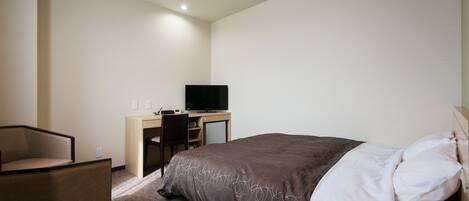 Una habitación de hotel con una cama, un escritorio con computadora y una silla.