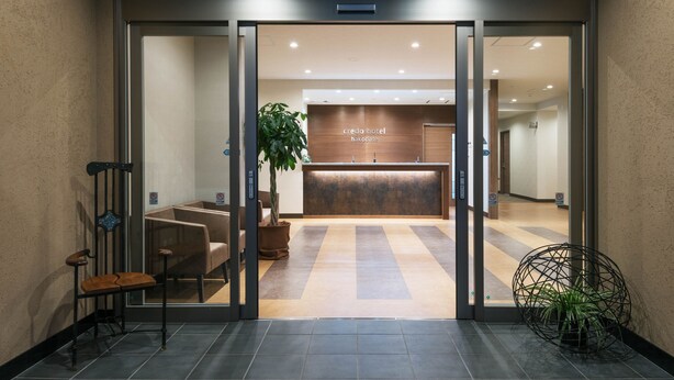 Et hotelreceptionsområde med en træreception, siddepladser og en potteplante.