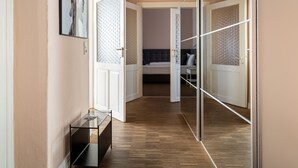 Un pasillo con una puerta de cristal que da a un dormitorio. La habitación tiene una cama, una mesita de noche y un espejo.