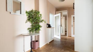 A hallway with a potted plant, a round table, and a mirror on the wall.