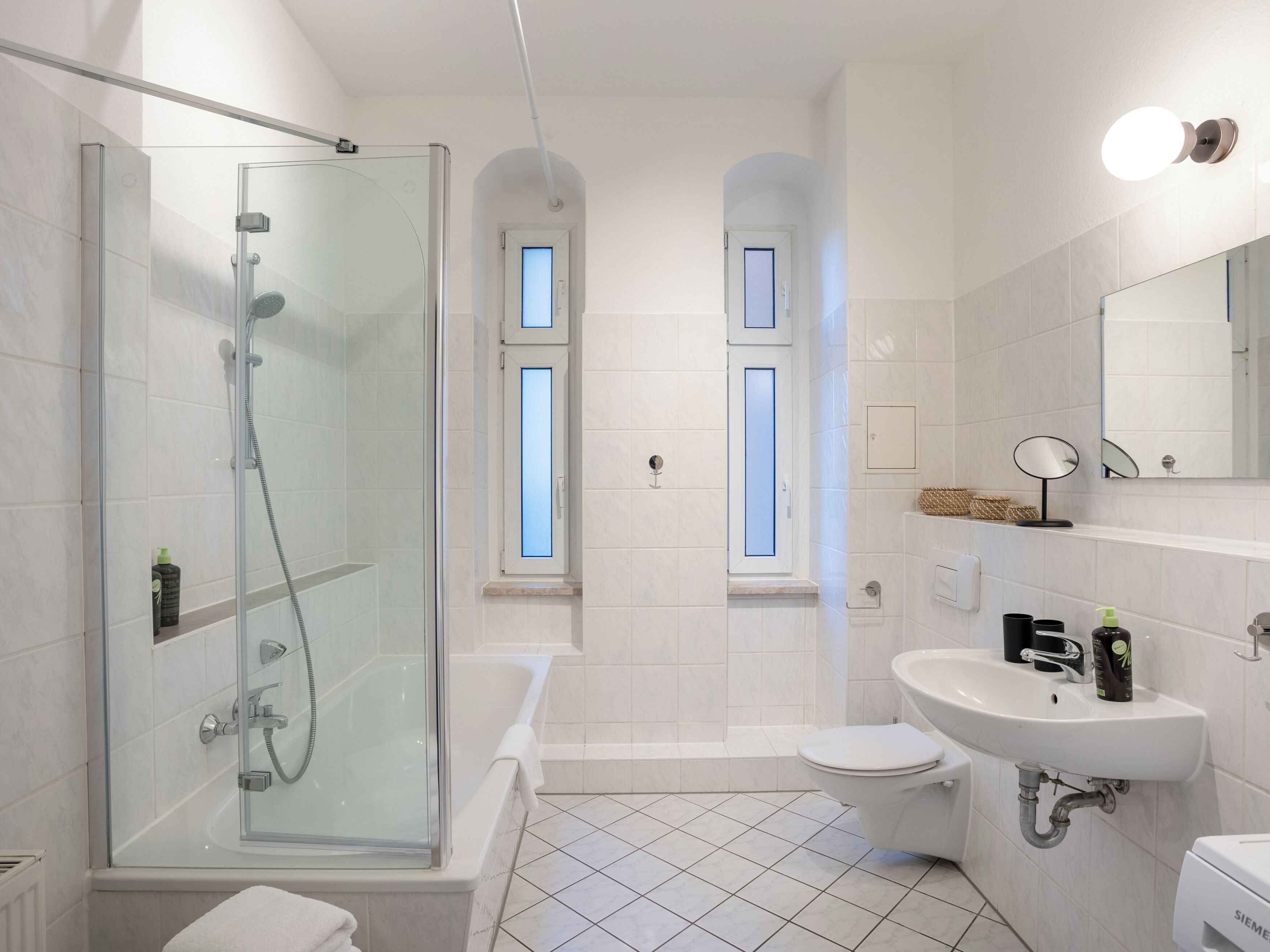 A modern bathroom with a glass-enclosed shower, a bathtub, a toilet, and a sink.