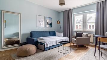 Un dormitorio moderno con cama, sofá, sillón, escritorio y un espejo grande.
