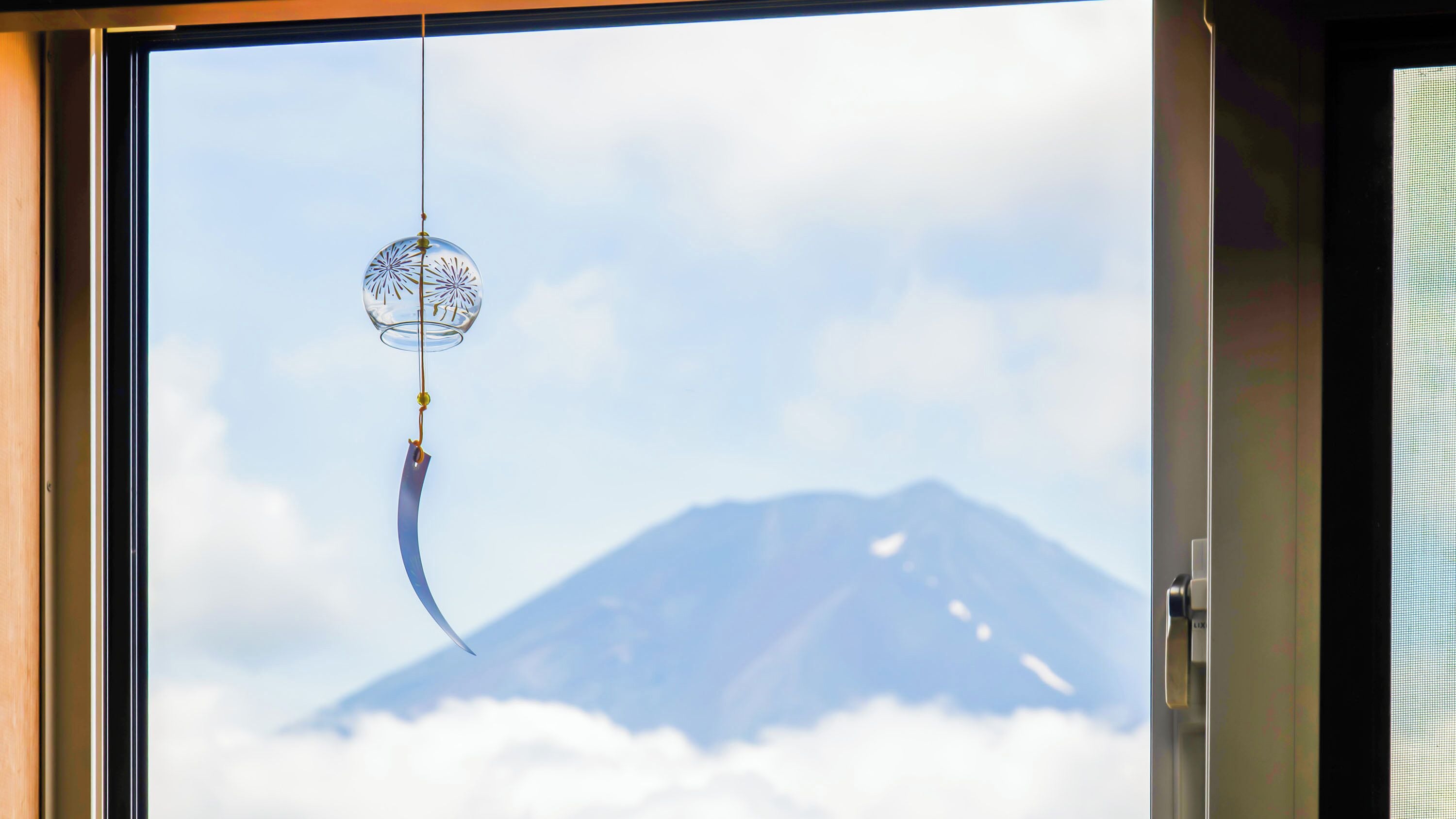 Une fenêtre donnant sur une montagne et des nuages.