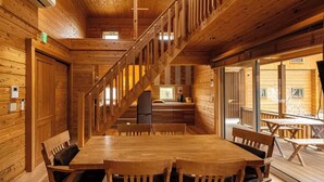 A wooden interior with a staircase, a dining area with tables and chairs, and large windows. - Fuyo No Yado (Fujiyoshida)