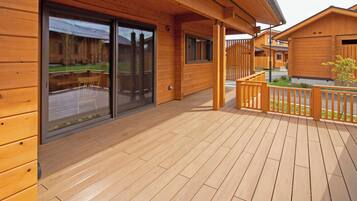 A wooden deck with a sliding glass door leading to a backyard.