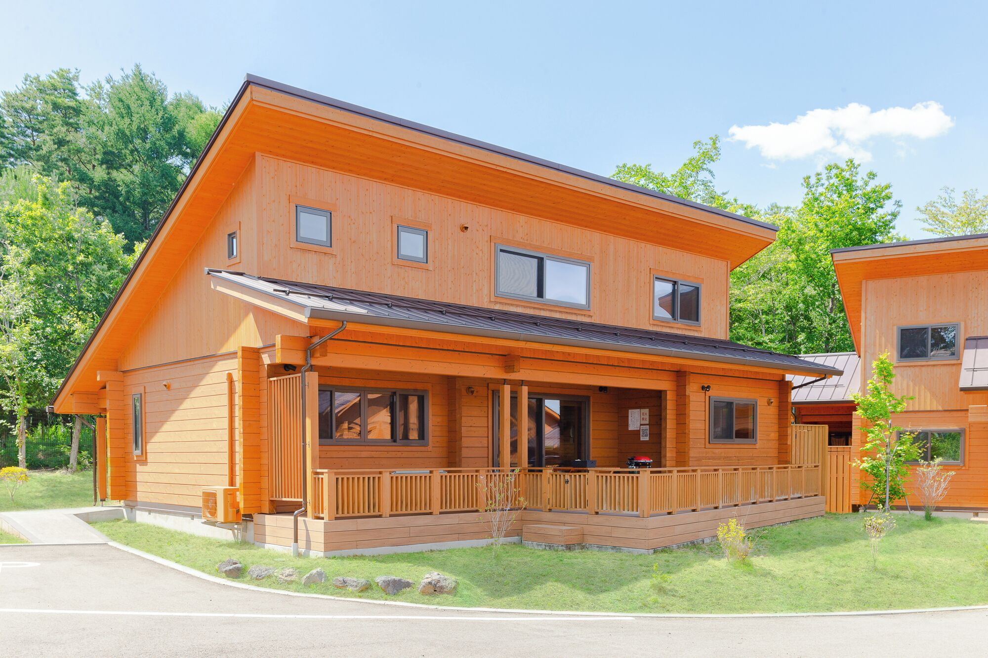 A two-story wooden house with a covered porch, a garage, and a small garden.