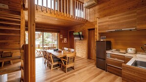 A wooden cabin interior with a dining area, kitchen, and a balcony. - Fuyo No Yado (Fujiyoshida)
