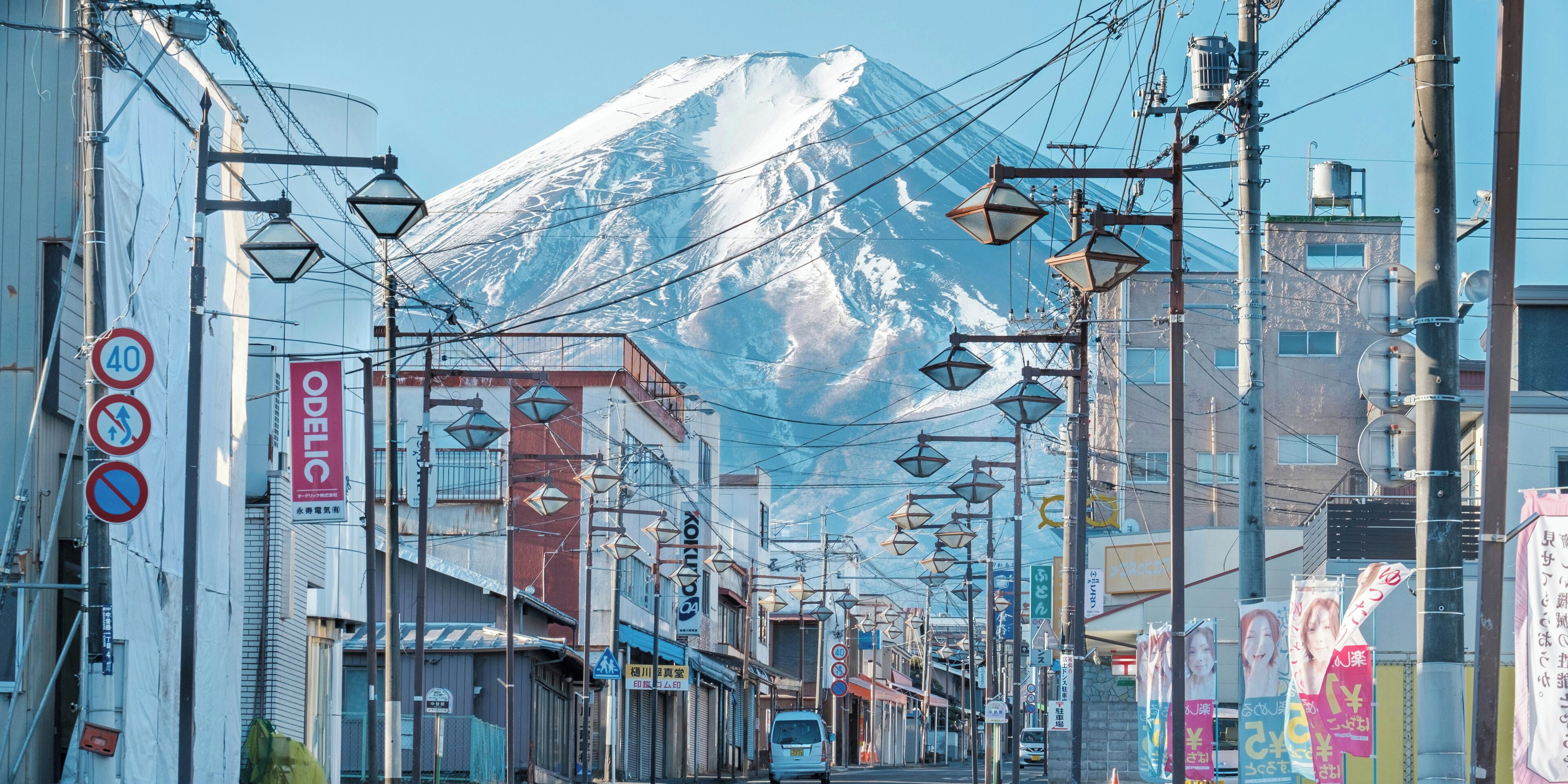 A street with buildings and a snow-capped mountain in the background.