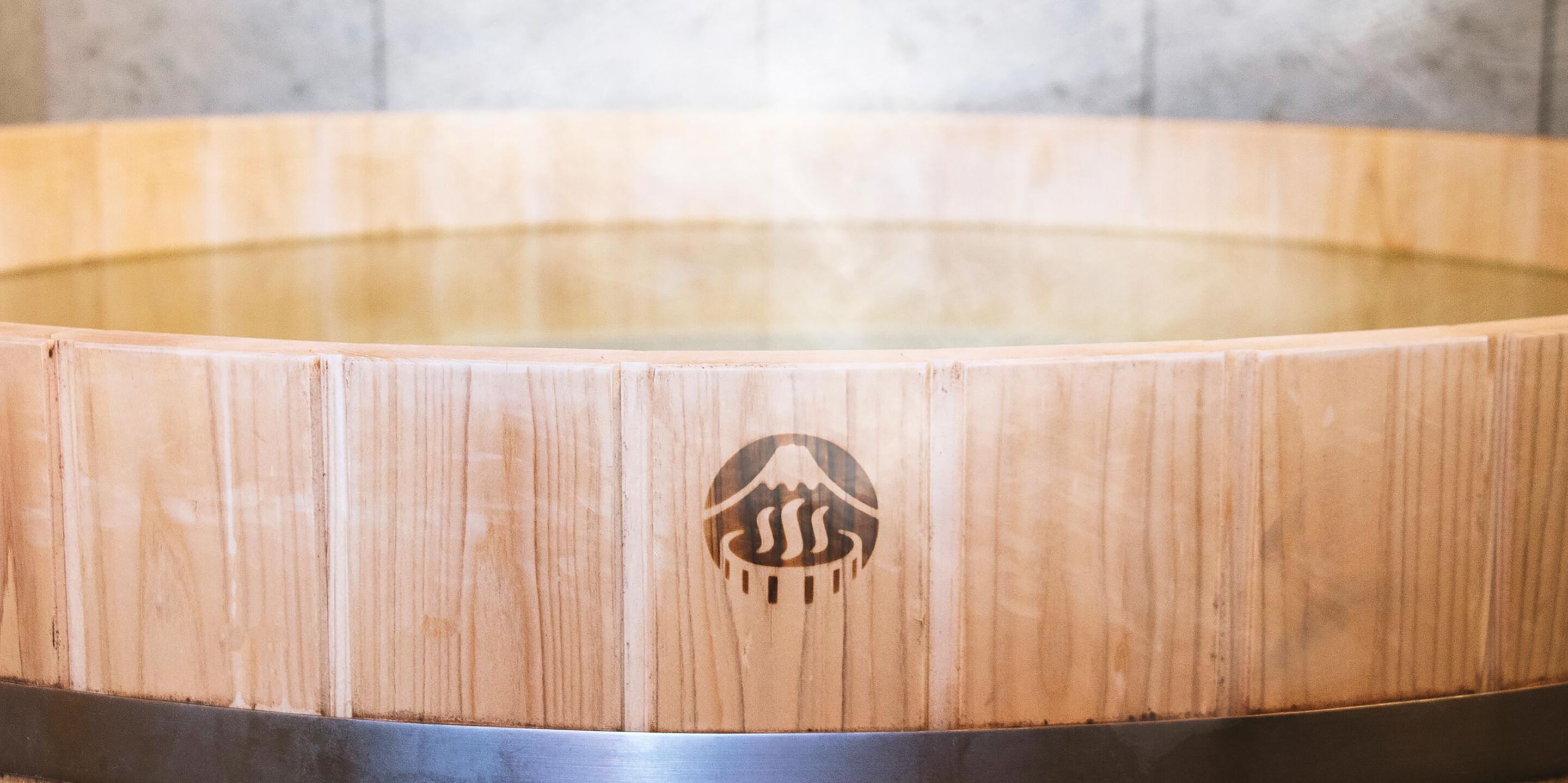Una vasca idromassaggio in legno con un logo al centro.