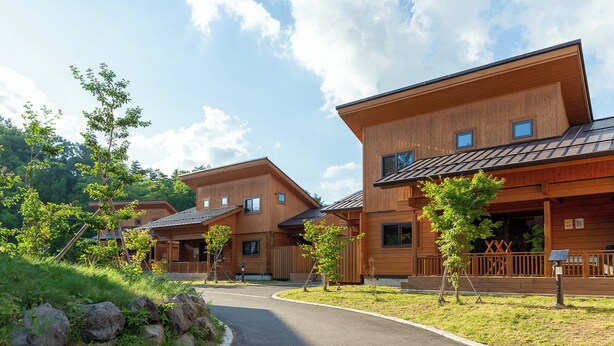 A modern wooden building with multiple levels, large windows, and a covered outdoor area with a wooden deck. - Fuyo No Yado (Fujiyoshida)