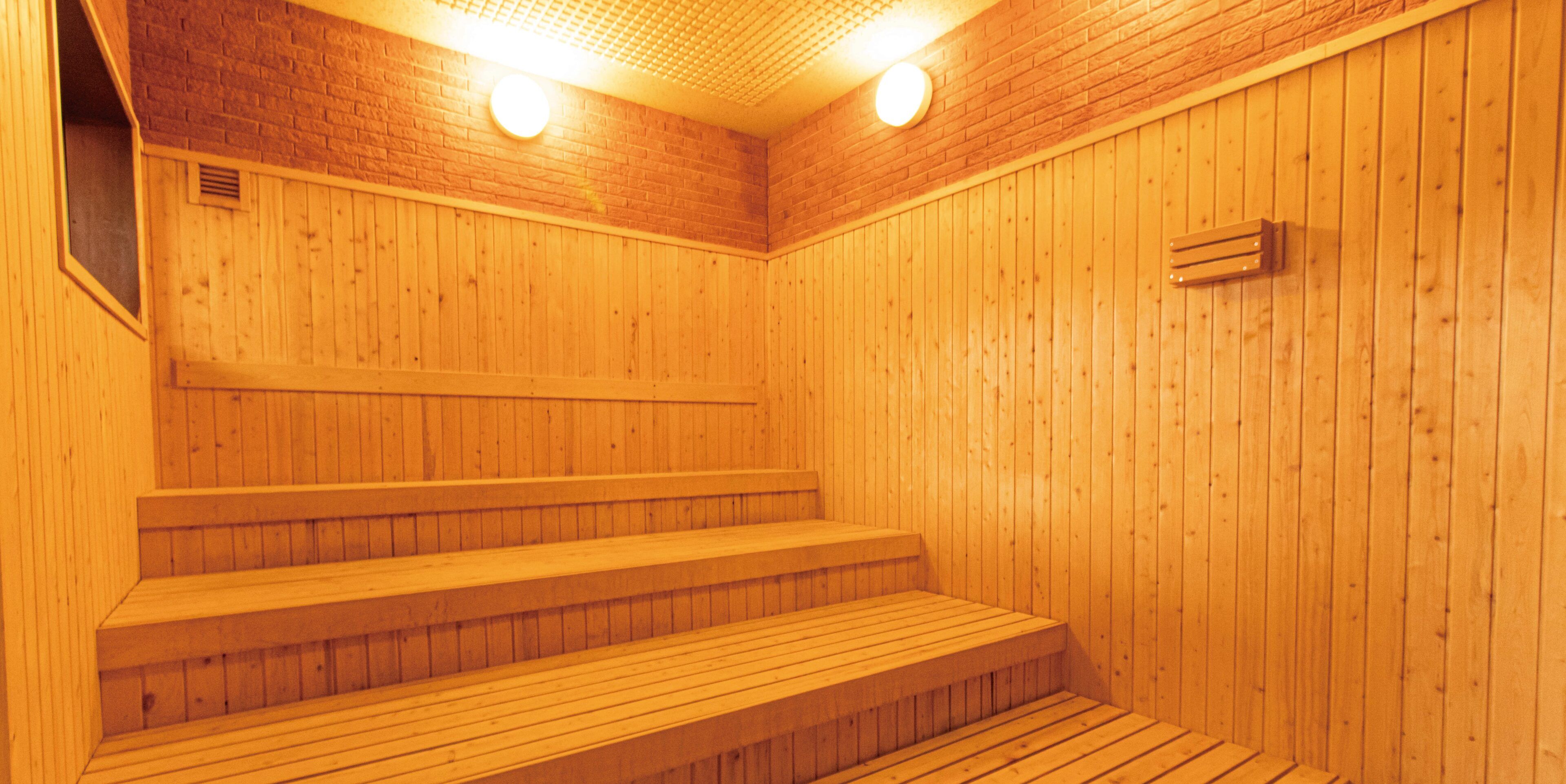 En træsauna med trin og bænk, med en murstensvæg og træpaneler.