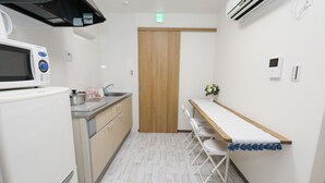 Cocina compacta con microondas, pileta y puerta de madera.