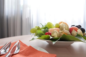 A table with a fruit bowl containing various fruits and a plate with cutlery. - Behringers Freizeit- & Tagungshotel (Goessweinstein)