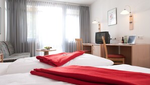 A hotel room with a bed, a desk with a computer, a chair, and a television. - Behringers Freizeit- & Tagungshotel (Goessweinstein)