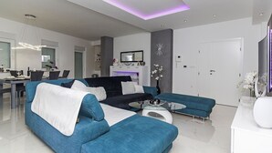Un salon moderne avec un canapé bleu, une table basse et un coin repas comprenant des chaises et une table.