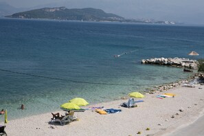 A beach with clear water, umbrellas, and lounge chairs.