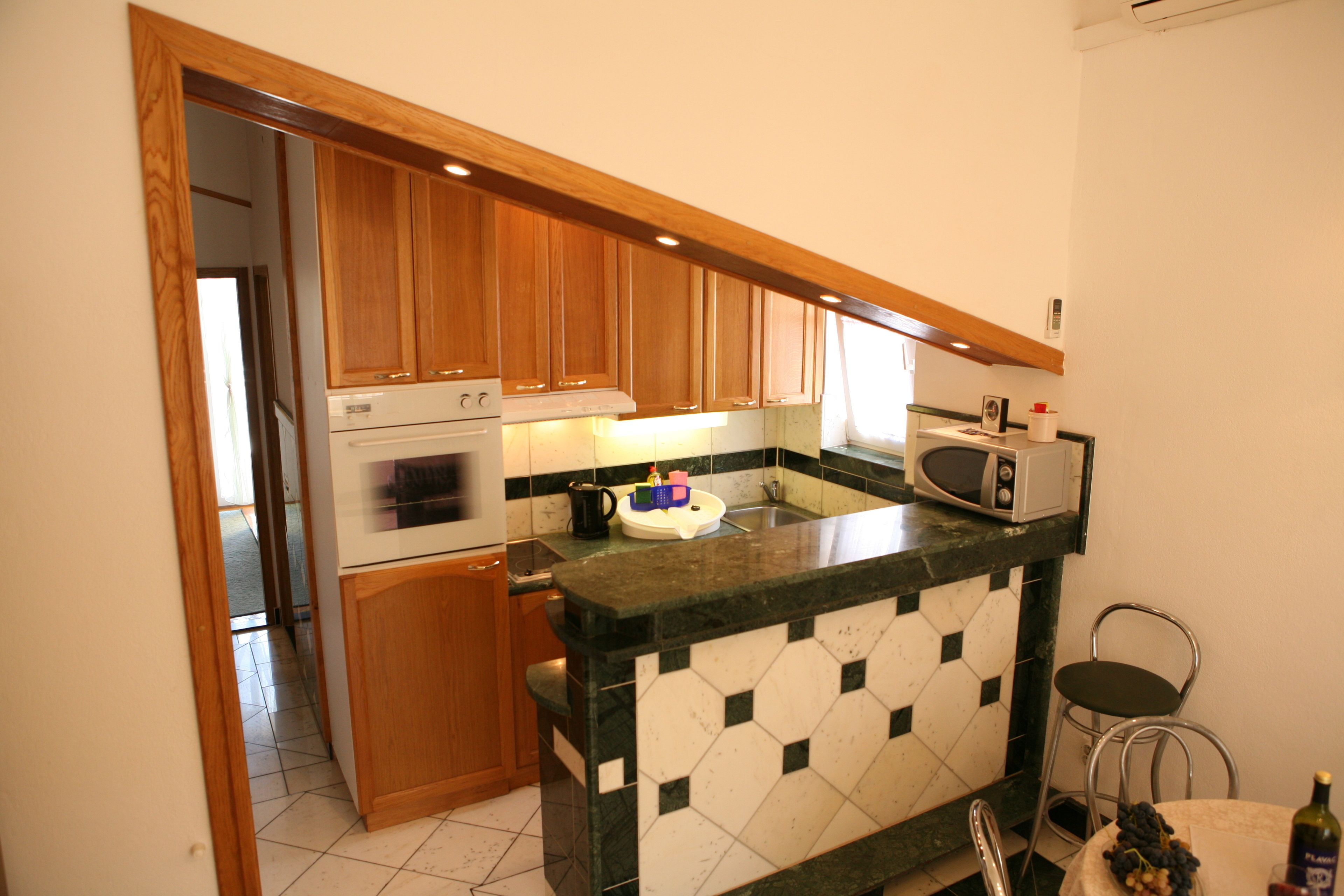 A kitchen with wooden cabinets, a microwave, and a tiled backsplash.