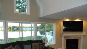 A living room with a large window, a fireplace, and a flat-screen TV.