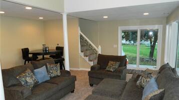 A living room with two sofas, a dining table, and a staircase leading to a balcony.