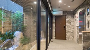A modern hotel lobby with a glass wall, a wooden door, and a marble wall. - Hotel Yu-shu (Osaka)