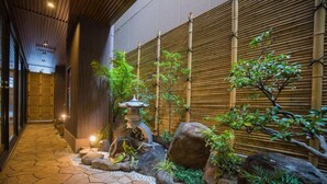 A traditional Japanese garden with a stone pathway, bamboo wall, and a lantern. - Hotel Yu-shu (Osaka)