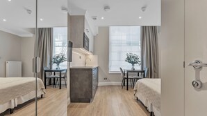 A modern hotel room with a bed, a desk, and a dining area. - Cleveland Residences Paddington (London)