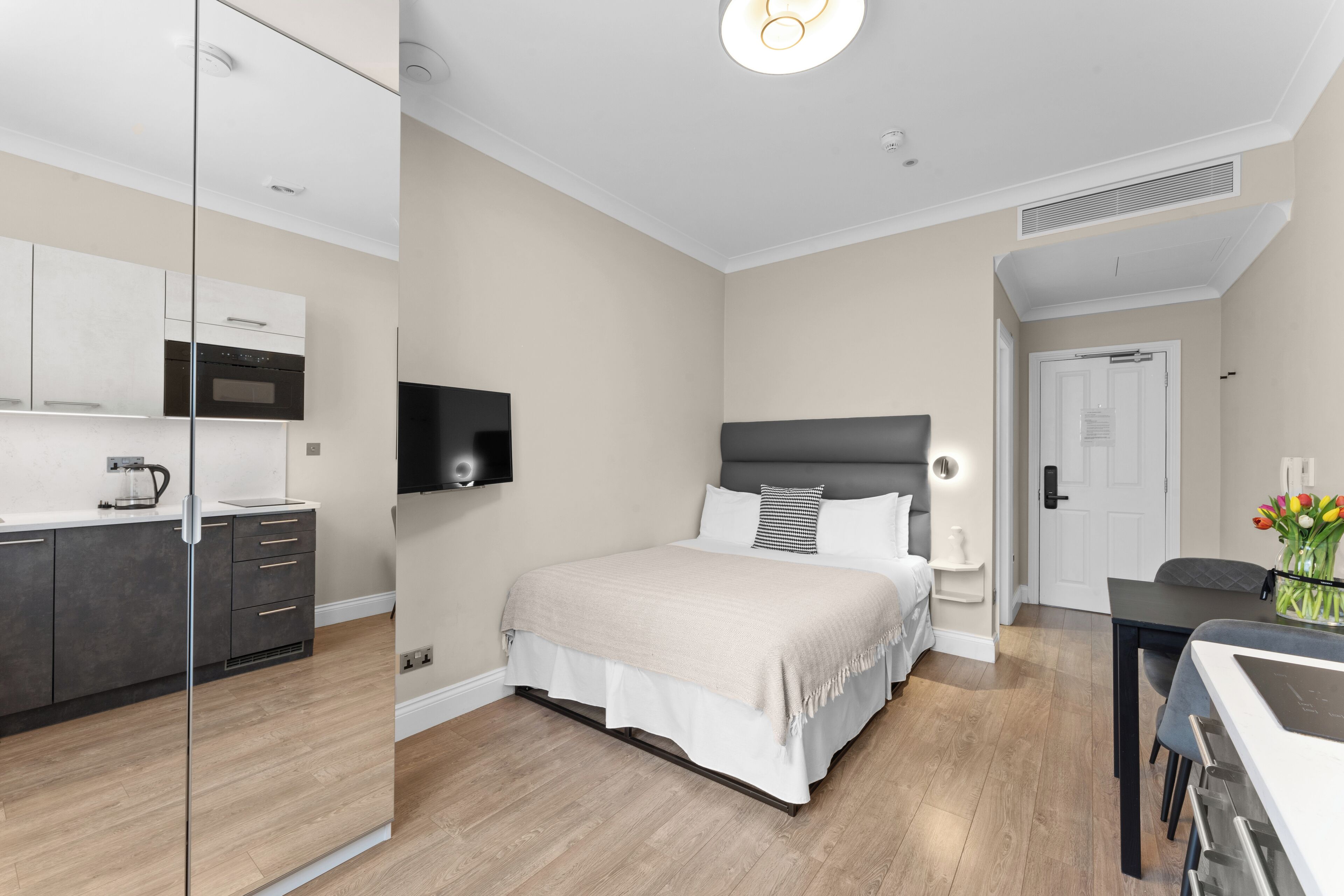 A modern bedroom with a bed, bedside table, and a TV mounted on the wall.