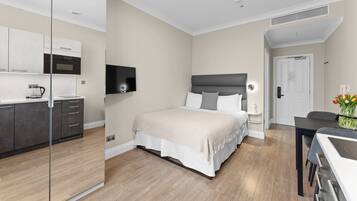 A modern bedroom with a bed, bedside table, and a TV mounted on the wall.