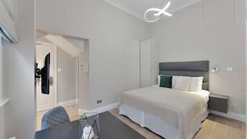 A modern bedroom with a large bed, bedside tables, a desk, and a chair.