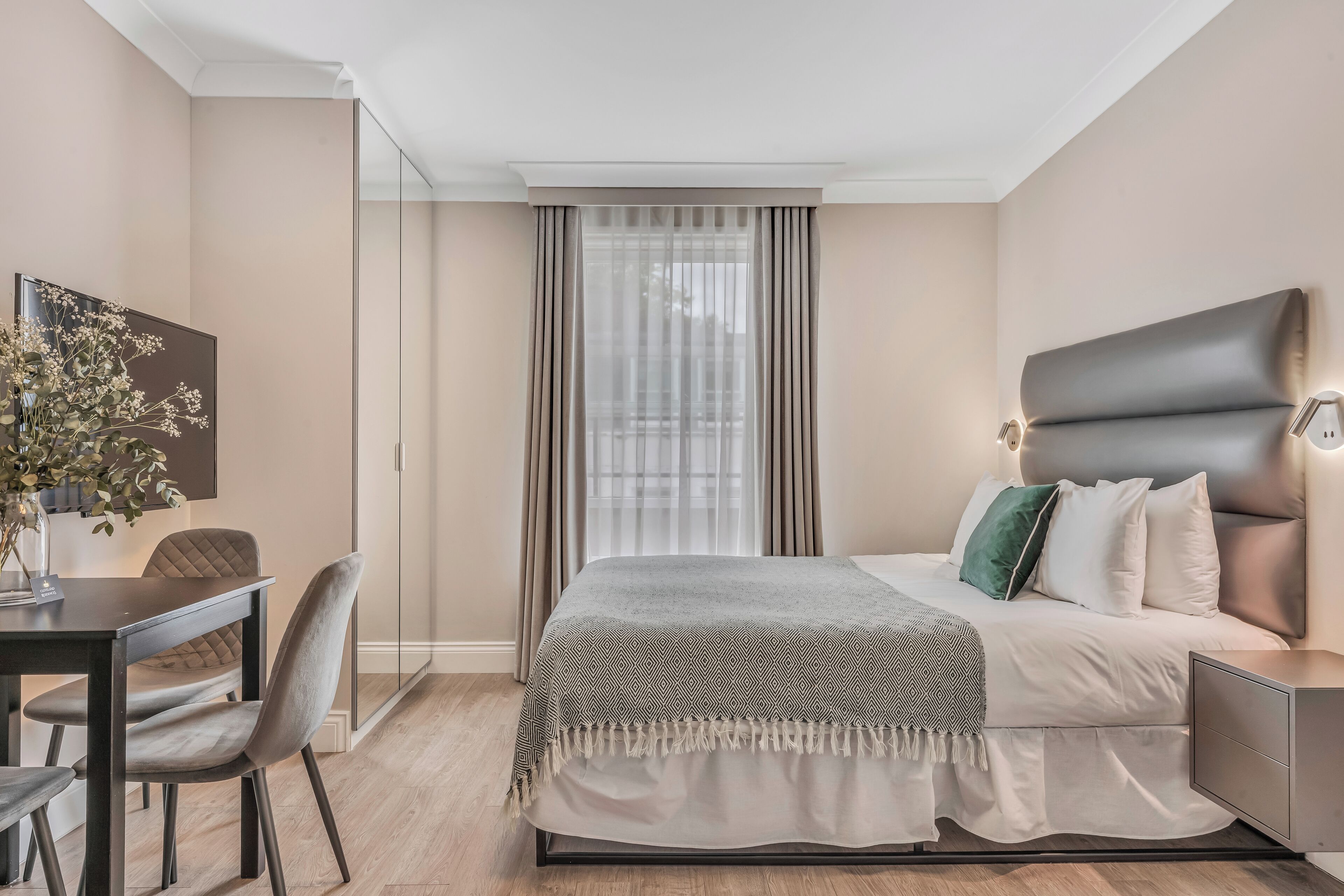 Un dormitorio moderno con una cama, una mesita de noche y un escritorio con una silla.