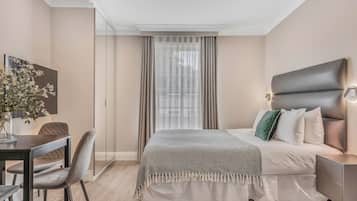 Un dormitorio moderno con una cama, una mesita de noche y un escritorio con una silla.