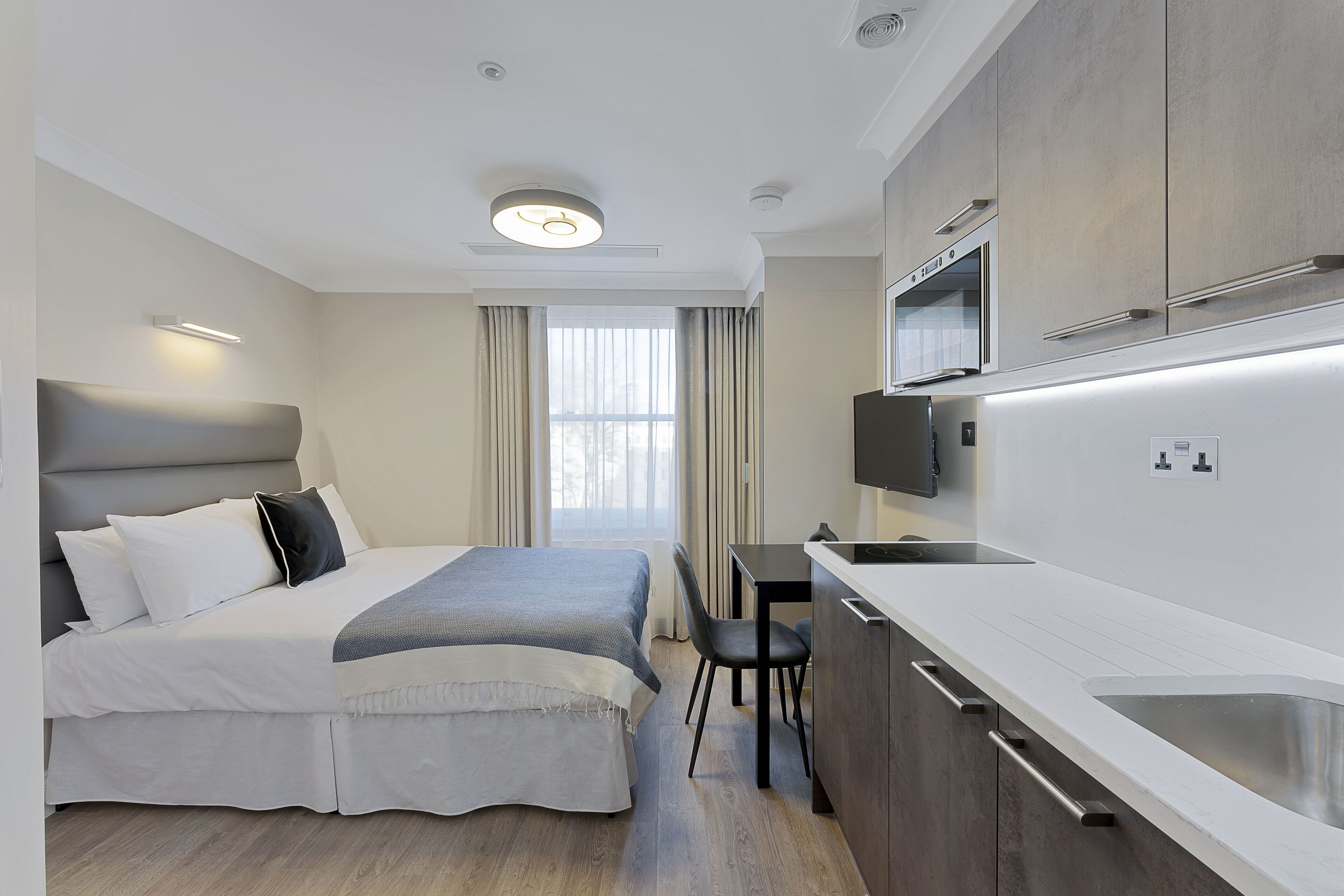 Une chambre d’hôtel moderne équipée d’un lit, d’un bureau et d’une kitchenette.