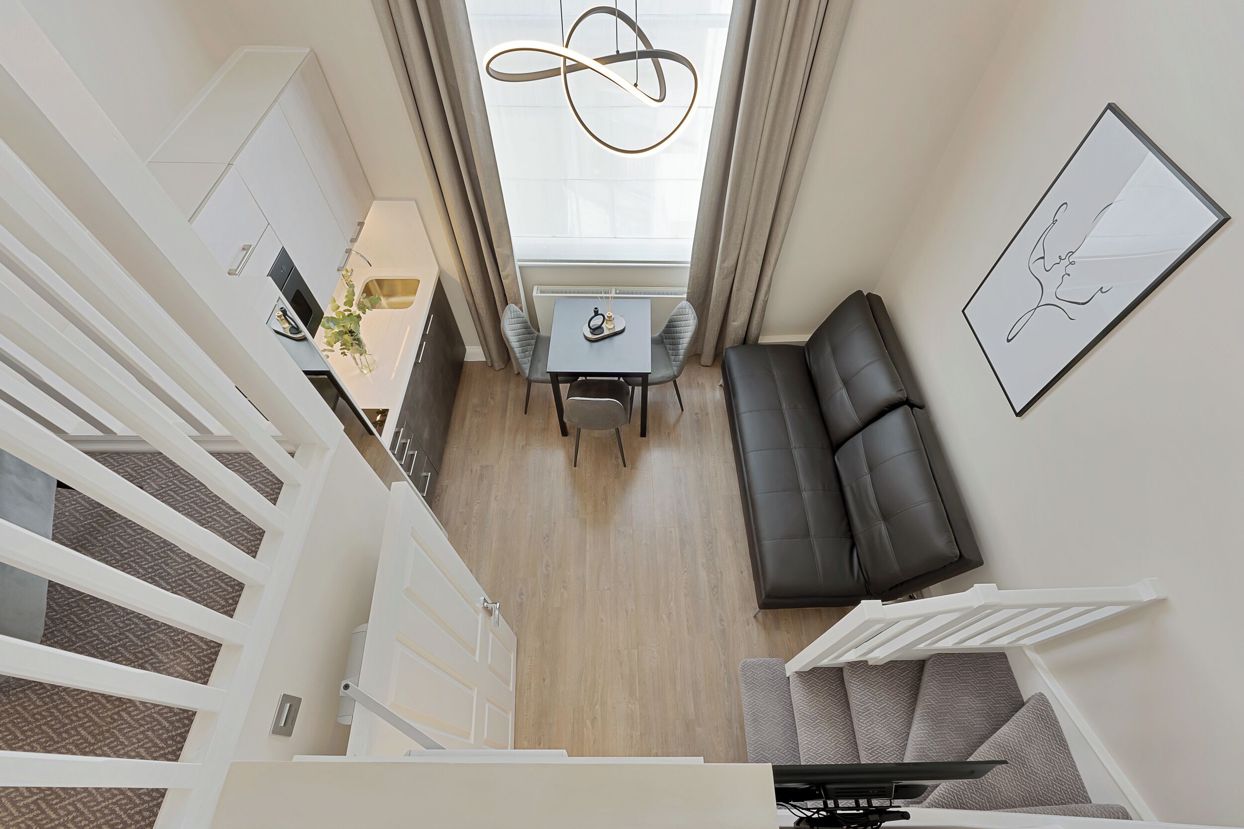 A modern kitchen with a dining area, a sofa, and a staircase.