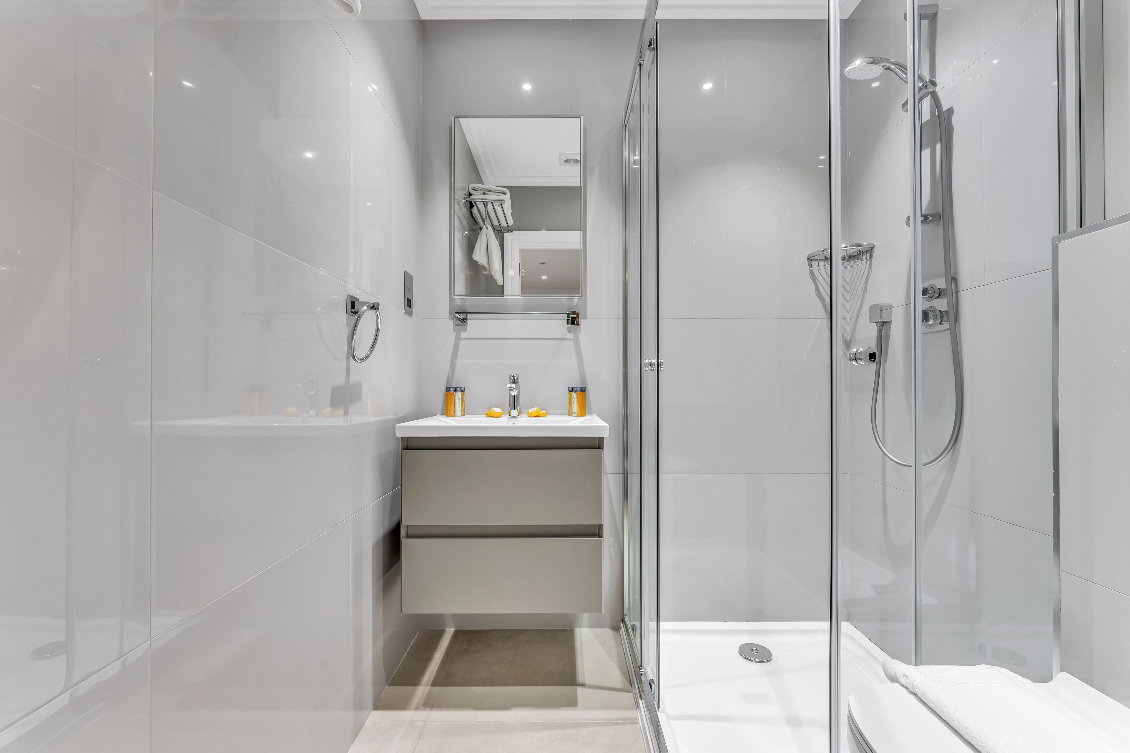 A modern bathroom with a glass-enclosed shower, a vanity with a mirror, and a sink.