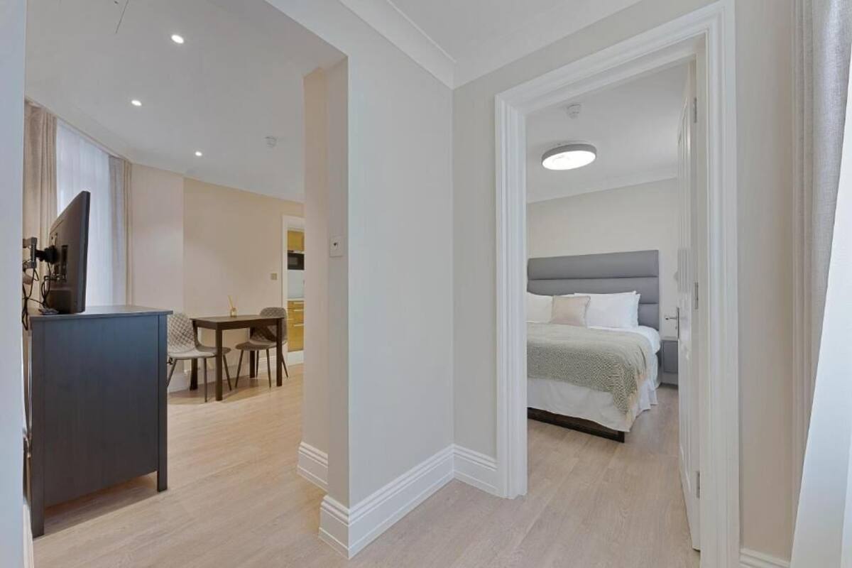 A modern hotel room with a bed, a desk, and a dining area.