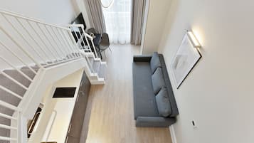 Una sala de estar moderna con un sofá gris, una escalera y un comedor.
