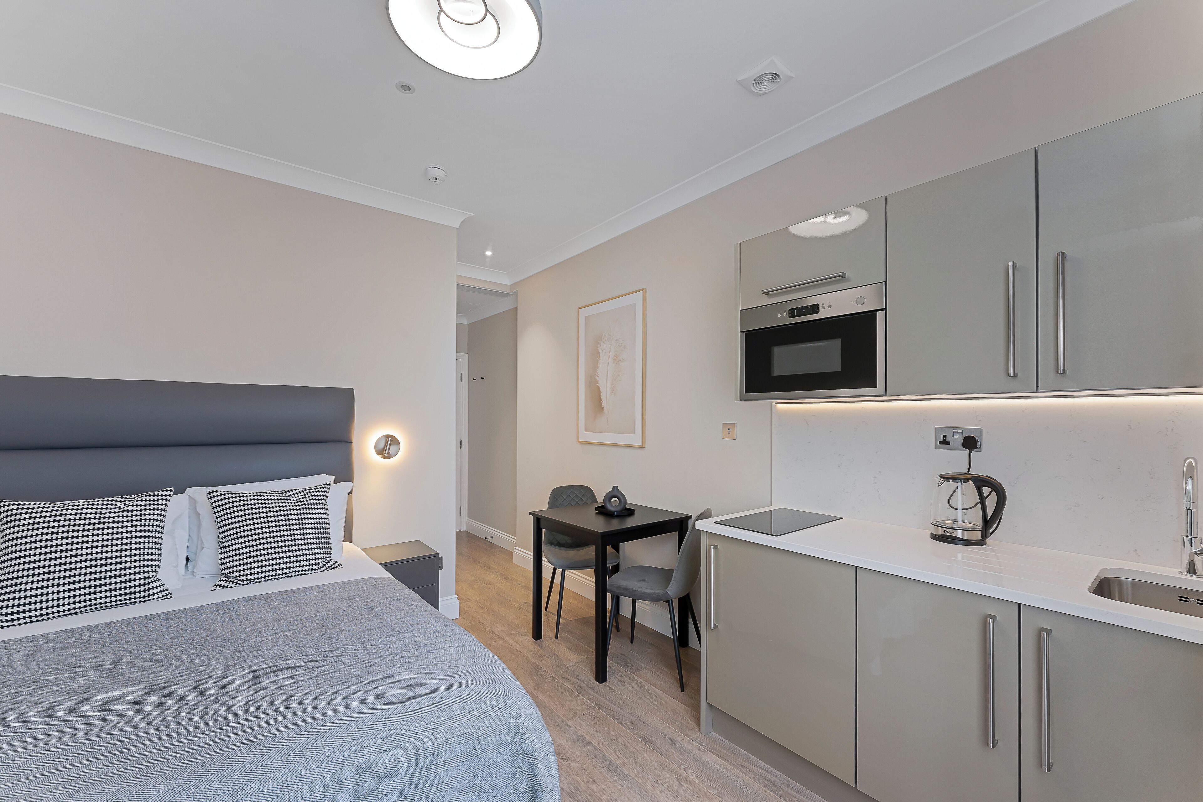 Et moderne hotelværelse med seng, lille skrivebord og tekøkken.