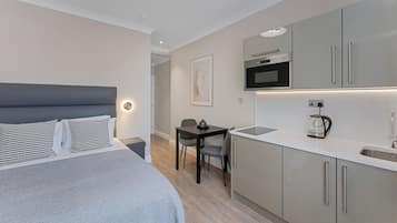 Et moderne hotelværelse med seng, lille skrivebord og tekøkken.