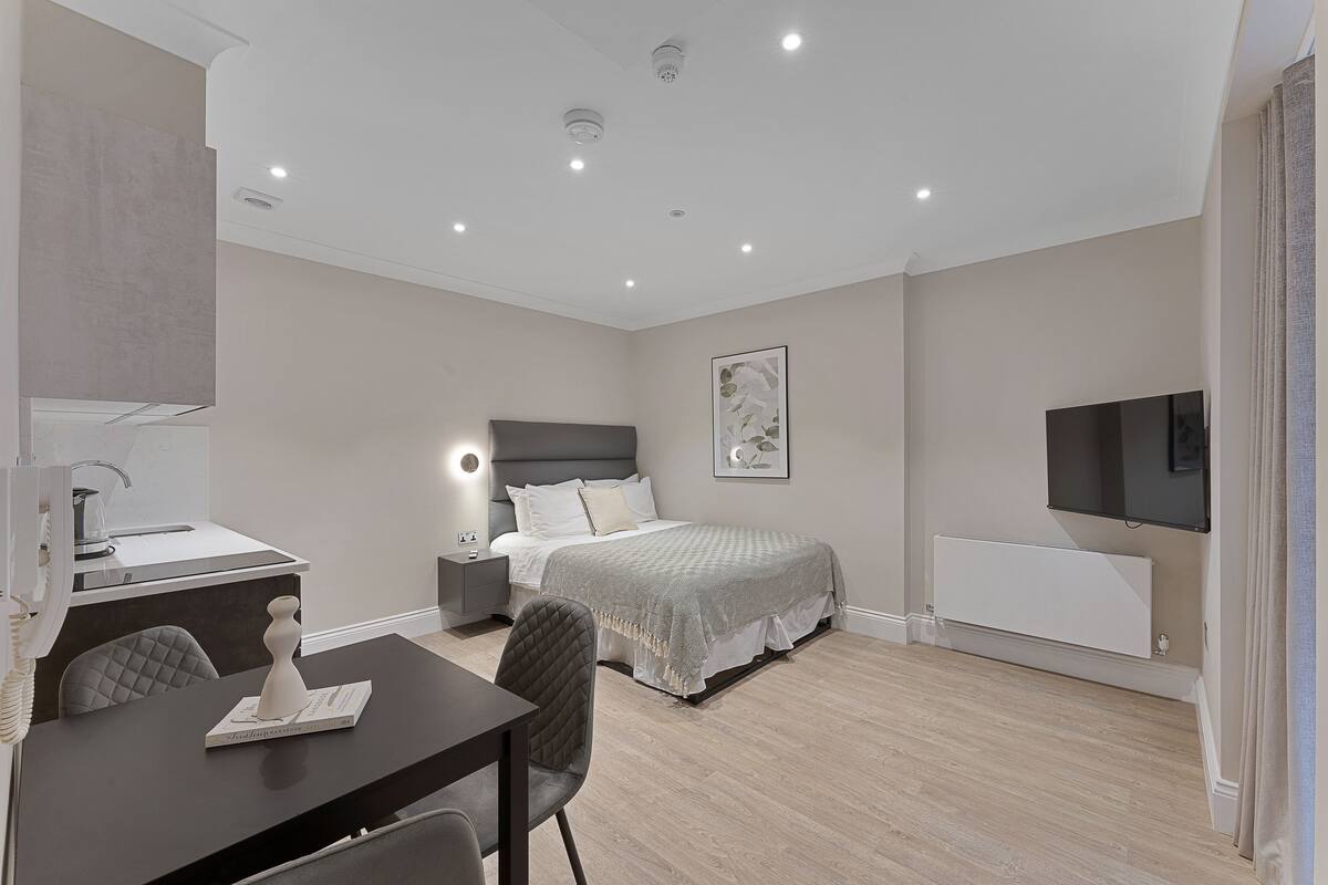 A modern bedroom with a bed, bedside table, lamp, and a TV mounted on the wall.
