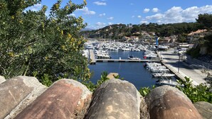 A marina with boats docked, surrounded by greenery and buildings in the background. - T2 vue mer 180° Avec balcon, Air-conditioned, direct access to the sea, Parking, Piscine (Saint-Cyr-sur-Mer)