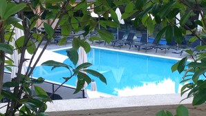 A swimming pool with lounge chairs and a view of a building in the background. - T2 vue mer 180° Avec balcon, Air-conditioned, direct access to the sea, Parking, Piscine (Saint-Cyr-sur-Mer)